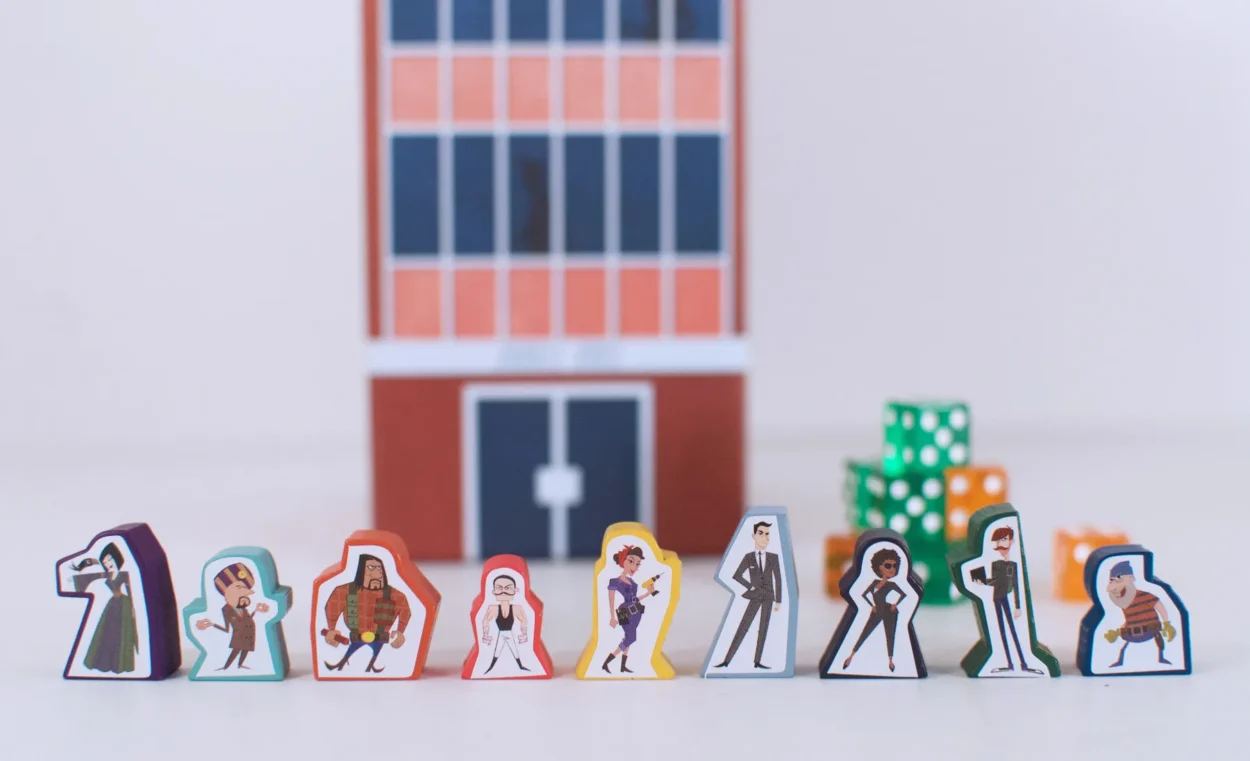 birgle bros game box, which looks like a three story office building, with the wooden pawns of the characters from the game along the front of the box
